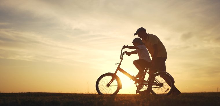 Dad teaching son to ride a bike.