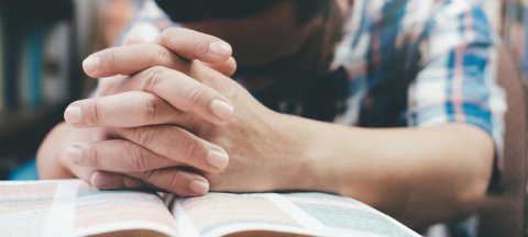 guy praying with a Bible